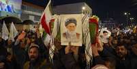 Procissão simbólica noturna no Irã, com a multidão carregando bandeiras e fotos do ex-líder supremo do Irã, o aiatolá Ali Khamenei  Foto: Anadolu via Getty Images / BBC News Brasil