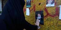 Mulher presta homenagem diante de um retrato de Ali Khamenei em Teer&atilde;; funeral do ex-l&iacute;der supremo mobiliza multid&otilde;es e &eacute; tratado pelo regime iraniano como uma demonstra&ccedil;&atilde;o de for&ccedil;a pol&iacute;tica.  Foto: RFI