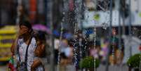 Extenso, Brasil sofre com dezenas de ondas de calor ao longo do ano. Na imagem, mulher se refresca em chafariz de Porto Alegre. (15/12/2023) Foto: RFI
