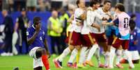 Dayot Upamecano, da Fran&ccedil;a, abatido ap&oacute;s a partida e a elimina&ccedil;&atilde;o de sua equipe, enquanto jogadores da Espanha celebram a classifica&ccedil;&atilde;o para a final da Copa do Mundo, em 14 de julho de 2026, no Dallas Stadium, Arlington, Texas, EUA.  Foto: REUTERS - Albert Gea / RFI