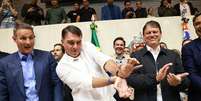 Derrite e Tarc&iacute;sio observam Fl&aacute;vio Bolsonaro fazer um gesto em alus&atilde;o a um jogo de videogame  Foto: Daniel Teixeira/Estad&atilde;o / Estad&atilde;o