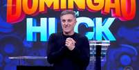 Luciano Huck divulgou dicas sobre os participantes da nova temporada da 'Dança dos Famosos', em 2026; estreia do quadro ocorrerá depois da divulgação da lista em 16 de agosto de 2026.  Foto: Reprodução de 'Domingão Com Huck' (2026)TV Globo / Estadão