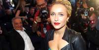 Hayden Panettiere, rodeada de fot&oacute;grafos, usa o cabelo preso, batom vermelho e um vestido verde com uma jaqueta de couro preta por cima.  Foto: Getty Images / BBC News Brasil