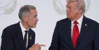 Mark Carney e Donald Trump durante a c&uacute;pula pela paz em Gaza, em 13 de outubro de 2025.  Foto: &copy; Evan Vucci / POOL/AFP/Archivos / RFI