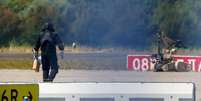 Imagem de arquivo. Um policial caminha ao lado de um rob&ocirc; de desativa&ccedil;&atilde;o de explosivos (EOD) no Aeroporto de Leipzig/Halle em Schkeuditz, Alemanha, em 5 de agosto de 2026, ap&oacute;s especialistas em explosivos terem examinado um drone encontrado perto de uma pista de pouso e decolagem.  Foto: REUTERS - Axel Schmidt / RFI
