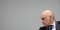 Alexandre de Moraes estende o bra&ccedil;o para pegar algo durante julgamento  Foto: Reuters / BBC News Brasil