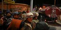 Pessoas que buscam por parentes desaparecidos e moradores da região aguardam enquanto militares formam um cordão de segurança após explosões que deixaram mortos e feridos no Regimento de Artilharia Mecanizada "Bolívar", em Viacha, Bolívia, em 4 de setembro de 2026.  Foto: REUTERS - Claudia Morales / RFI