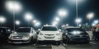 Foto: Cena noturna em um estacionamento bem iluminado com v&aacute;rios carros estacionados e postes de luz. ( Pexels) / G&aacute;vea News