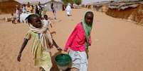 Jovens refugiadas sudanesas transportam água perto de uma seção eleitoral no campo de refugiados de Zamzam, nos arredores de El Fasher, em Darfur, no Sudão. (Imagem ilustrativa)  Foto: RFI