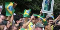 Apoiadores de Flávio Bolsonaro acenam com bandeiras do Brasil e quadro de Jair antes de carreata em Santa Bárbara d'Oeste  Foto: Felipe Rau/Estadão