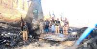 Combatentes houthis diante do que afirmam ser os destroços de um avião de combate saudita abatido, em local não especificado no Iêmen, em imagem extraída de um vídeo divulgado em 16 de setembro de 2026.  Foto: via REUTERS - Houthi Military Media / RFI
