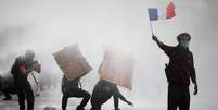 Manifestante mascarado segura bandeira francesa durante protestos de estudantes e confrontos com for&ccedil;as de ordem, em Paris, em 13 de outubro de 2026.  Foto: REUTERS - Sarah Meyssonnier / RFI