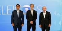 O mediador C&eacute;sar Tralli com os candidatos Fl&aacute;vio Bolsonaro (PL) e Lula (PT): debate de 2&ordm; turno na Globo foi o ponto alto de audi&ecirc;ncia na cobertura eleitoral de 2026  Foto: Fernando Fraz&atilde;o/Ag&ecirc;ncia Brasil
