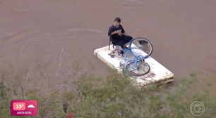 Menino improvisa embarcação para atravessar enchente no RS