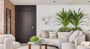 Com paleta ancorada no preto, apê tem painel ripado e piso de porcelanato