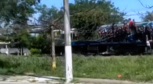 Passageiros viajam segurando em portas e janelas em trem da Baixada Fluminense