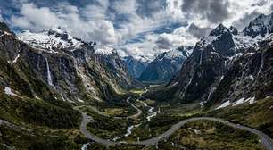 Com túneis escavados na rocha sólida e paredões com cachoeiras, a estrada desce as montanhas neozelandesas até o espetacular fiorde de Milford