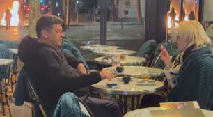 Casal toma drink perto de lixeira em chamas durante protestos em Paris