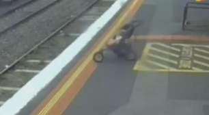 Carrinho com bebê cai de plataforma sobre trilhos de trem