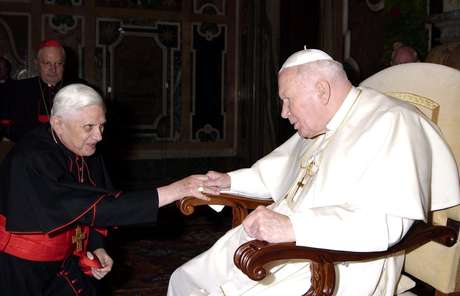 Em 2005, o então cardeal Ratzinger foi fotografado cumprimentando o papa João Paulo II, que morreria no mesmo ano <p>Em 2005, o então cardeal Ratzinger foi fotografado cumprimentando o papa João Paulo II, que morreria no mesmo ano</p>
