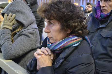 Mulher reza diante de um dos telões durante o início da noite fria em São Pedro Mulher reza diante de um dos telões durante o início da noite fria em São Pedro