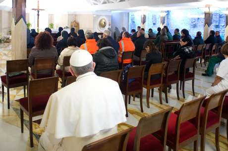 OSSERVATORE ROMANO / AFP Francisco ora ao lado de empregados do Vaticano antes de celebrar missa na capela de Santa Marta, no Vaticano
