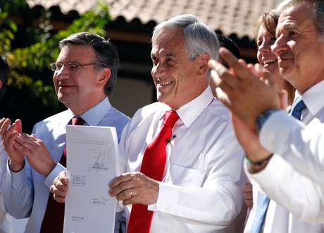 UPI <p>Los ministro de Desarrollo Social, Joaquín Lavín, y de Economía, Felipe Larraín, junto al presidente Sebastián Píñera durante la promulgación de la ley que establece el "bono marzo".</p>