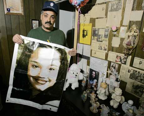 AP Felix DeJesus sostiene un afiche con la imagen de su hija desaparecida en una foto de archivo del 3 de marzo del 2004 frente a un altar de homenaje en la sala de su casa en Cleveland.