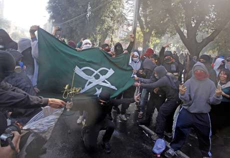 Manifestantes encapuzados queimam bandeira retirada de prédio da polícia durante protesto contra políticas de educação do governo em Valparaíso na terça-feira Manifestantes encapuzados queimam bandeira retirada de prédio da polícia durante protesto contra políticas de educação do governo em Valparaíso na terça-feira