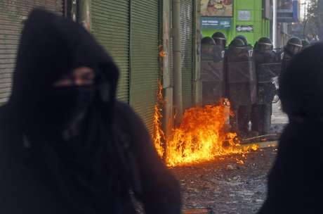 Manifestantes encapuzados são vistos durante confronto com a polícia na terça-feira, em Valparaíso Manifestantes encapuzados são vistos durante confronto com a polícia na terça-feira, em Valparaíso