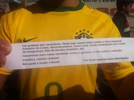 Papéis entregues antes do jogo pediam que torcedores cantassem o Hino Nacional de costas; iniciativa não teve muita adesão <p>Papéis entregues antes do jogo pediam que torcedores cantassem o Hino Nacional de costas; iniciativa não teve muita adesão</p>