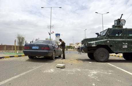 Soldado faz uma revista em um carro em Sanaa Soldado faz uma revista em um carro em Sanaa