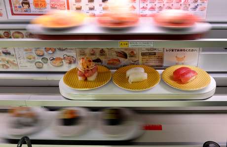 Balcões com três decks de raias de alta velocidade fornecem sushi diretamente à pessoa que fez o pedido em uma tela sensível ao toque multilínguas Balcões com três decks de raias de alta velocidade fornecem sushi diretamente à pessoa que fez o pedido em uma tela sensível ao toque multilínguas