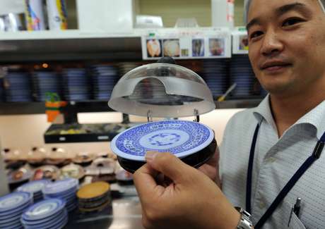 Prato com domo transparente se abre automaticamente quando os comensais selecionam o prato. Enquanto a tampa mantém o sushi úmido e limpo, ele também contém um microchip que diz aos gestores o tipo de peixe que está circulando nas esteiras e há quanto tempo está exposto Prato com domo transparente se abre automaticamente quando os comensais selecionam o prato. Enquanto a tampa mantém o sushi úmido e limpo, ele também contém um microchip que diz aos gestores o tipo de peixe que está circulando nas esteiras e há quanto tempo está exposto