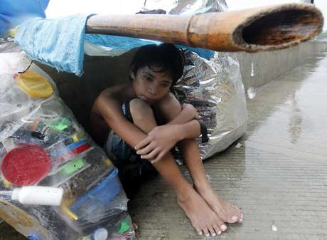 Menino improvisa cobertura para se esconder da chuva em Manila Menino improvisa cobertura para se esconder da chuva em Manila