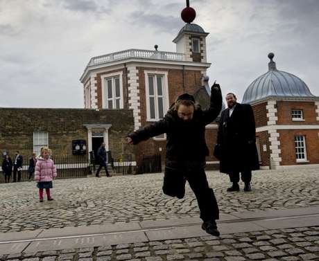 Criança pula sobre linha que representa a divisão do mundo em fusos horários no Observatório Real de Londres, em Greenwich Criança pula sobre linha que representa a divisão do mundo em fusos horários no Observatório Real de Londres, em Greenwich