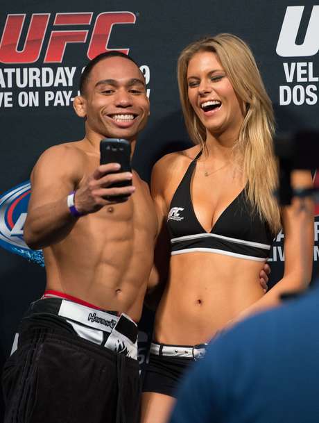 Getty Images John Dodson esbanja carisma na pesagem do UFC; ao subir para a pesagem, o peso mosca aproveita para tirar uma foto com a ring girl Chrissy Blair