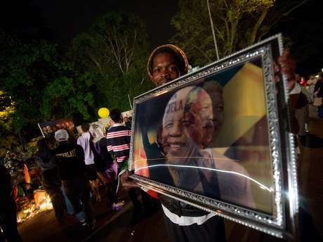 Homem segura um quatro com o rosto de Nelson Mandela durante as homenagens ao líder sul-africano <p>Homem segura um quatro com o rosto de Nelson Mandela durante as homenagens ao líder sul-africano</p>