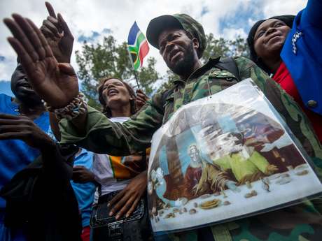 Homem segura um cartaz em que Mandela aparece no lugar de Cristo na Santa Ceia <p>Homem segura um cartaz em que Mandela aparece no lugar de Cristo na Santa Ceia</p>
