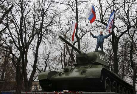 Manifestante exibe bandeiras da Rússia e da Crimeia em um antigo tanque das Forças Armadas da União Soviética, durante protesto em frente ao prédio do governo de Simferopol, na Crimeia <p>Manifestante exibe bandeiras da Rússia e da Crimeia em um antigo tanque das Forças Armadas da União Soviética, durante protesto em frente ao prédio do governo de Simferopol, na Crimeia</p>