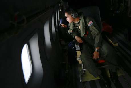Membro da Força Aérea da Malásia olha pela janela de um avião da durante operação de busca para encontrar o avião desaparecido da Malaysia Airlines, no Estreito de Malaca, nesta quinta-feira, 13 de março <p>Membro da Força Aérea da Malásia olha pela janela de um avião da durante operação de busca para encontrar o avião desaparecido da Malaysia Airlines, no Estreito de Malaca, nesta quinta-feira, 13 de março</p>