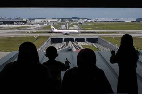 Pessoas olham para fora de uma janela enquanto um Boeing da Malaysia Airlines taxia no Aeroporto Internacional de Kuala Lumpur, na Malásia, em 14 de junho <p>Pessoas olham para fora de uma janela enquanto um Boeing da Malaysia Airlines taxia no Aeroporto Internacional de Kuala Lumpur, na Malásia, em 14 de junho</p>