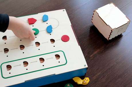 Primo é composto de três partes: um robô em forma de cubo (à direita), uma interface de controle e botões de comando. Estes devem ser inseridos na interface para criar a sequência de movimentos do robô <p>Primo é composto de três partes: um robô em forma de cubo (à direita), uma interface de controle e botões de comando. Estes devem ser inseridos na interface para criar a sequência de movimentos do robô</p>