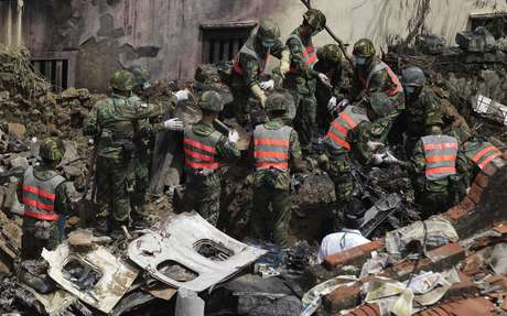 Oficiais observam destroços do avião que caiu em Taiwan na última quinta-feira Oficiais observam destroços do avião que caiu em Taiwan na última quinta-feira