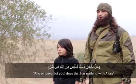 O menino aparece do lado de um jihadista adulto que fala por alguns segundos O menino aparece do lado de um jihadista adulto que fala por alguns segundos
