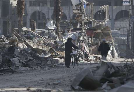 Homens caminham na cidade rebelde de Douma, próxima a Damasco, danificada pelos bombardeios do regime de Bashar al Assad <p>Homens caminham na cidade rebelde de Douma, próxima a Damasco, danificada pelos bombardeios do regime de Bashar al Assad</p>