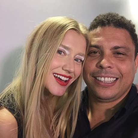 Jogador tira selfie ao lado da namorada em bastidores de desfile Jogador tira selfie ao lado da namorada em bastidores de desfile