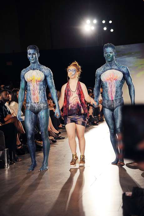 Madeline Stuart fez outra entrada para Hendrick Vermeulen, com shorts e camiseta, ao lado de dois modelos com pinturas que remetem aomfilme Avatar Madeline Stuart fez outra entrada para Hendrick Vermeulen, com shorts e camiseta, ao lado de dois modelos com pinturas que remetem aomfilme Avatar