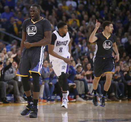 Draymond Green (23), de los Warriors de Golden State, reacciona tras un triple de Klay Thompson (derecha) ante el jugador de los Kings de Sacramento Rudy Gay (centro), durante la primera mitad del juego de la NBA que enfrentó a ambos equipos, el 28 de noviembre de 2015, en Oakland, California.