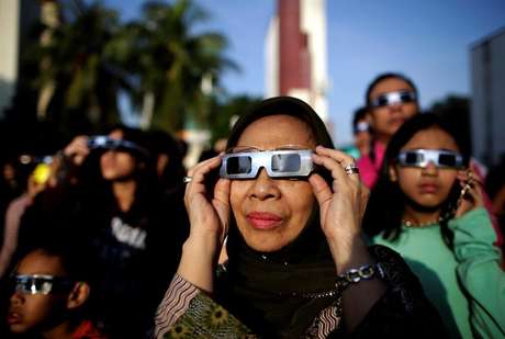 Varias personas utilizan gafas para observar el eclipse de sol en los alrededores del planetario en Yakarta